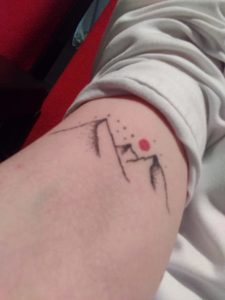 tatouage en forme de montagnes avec un soleil rouge