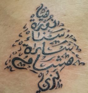 Tatouage en forme de cèdre qui contient des prénoms.