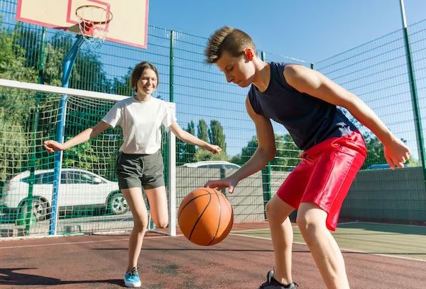 فتاة وصبي يلعبان كرة السلة